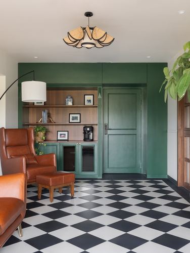 Living room corner with green built-in shelving, leather armchair and black-white checkered floor