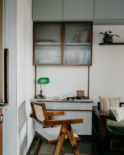 Study nook with cane chair, wood desk, and reeded glass cabinet above