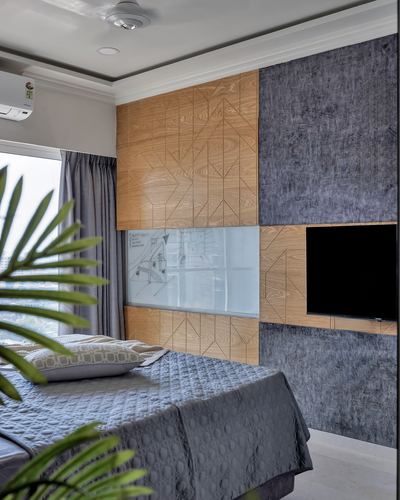Bedroom with geometric wood and grey fabric panelled wall behind bed and tv