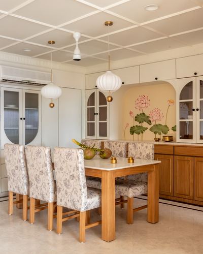 Dining room with coffered ceiling, floral upholstered chairs, and a lotus-mural niche above a wooden sideboard