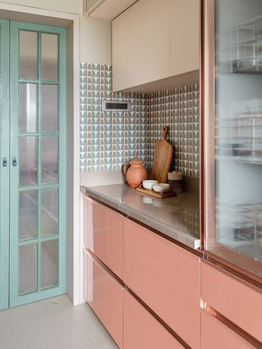 Pastel pink glossy kitchen cabinets with patterned tile backsplash and mint green glazed door