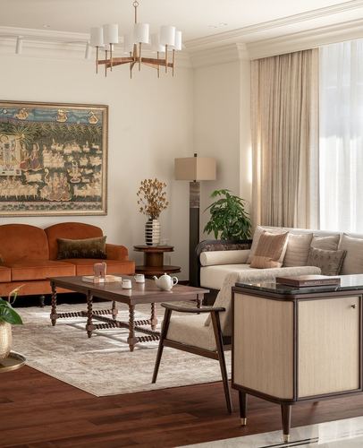Living room with rust velvet sofa, dark wood coffee table, framed miniature painting, and multi-arm chandelier