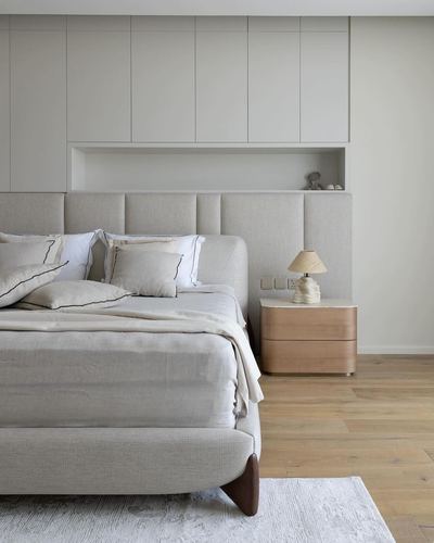 Neutral bedroom with channel-tufted headboard wall, wood nightstand, and recessed display niche
