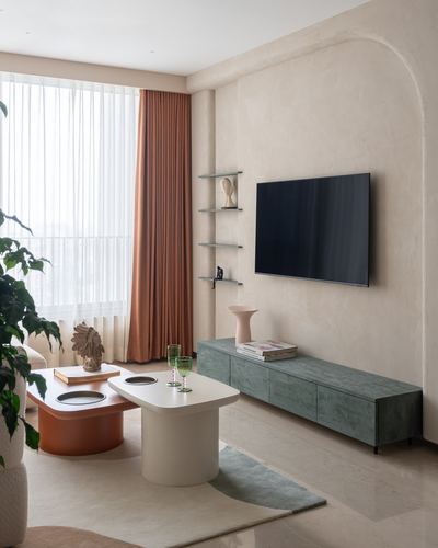 Living room with arched plaster wall, wall-mounted TV, green sideboard and layered coffee tables