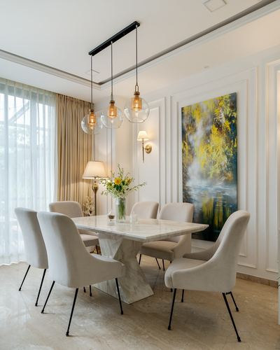 Neo-classical dining room with marble table, beige upholstered chairs, and amber glass pendant lights