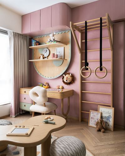 Pink nursery with scalloped wooden shelf, desk, boucle chair, and wall climbing ladder with rings