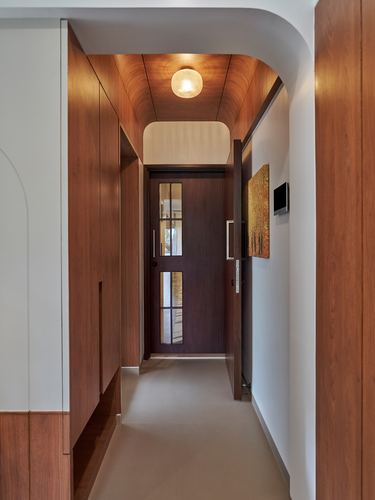 Narrow wood-panelled entrance corridor curving toward a glazed dark wooden front door