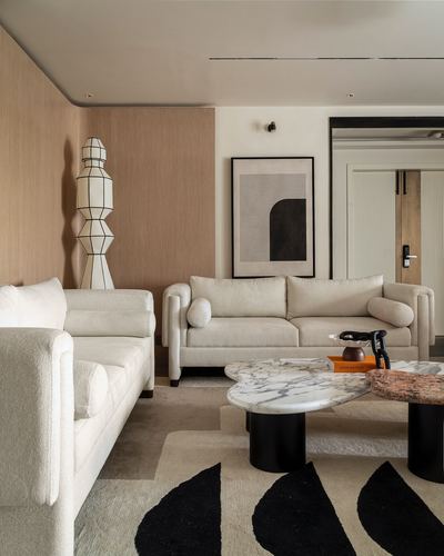 Beige living room with boucle sofas, marble coffee tables, and a sculptural floor lamp