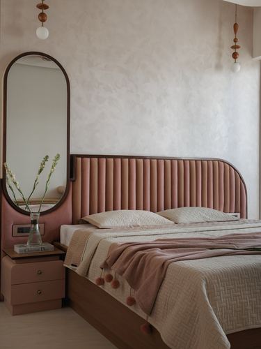 Pink channel-tufted headboard bed beside arched mirror and pink nightstand in textured-wall bedroom
