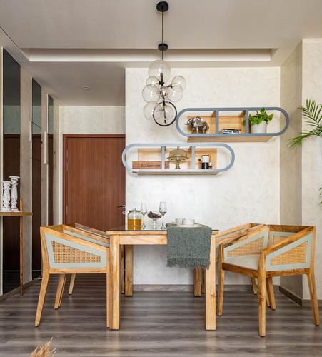 Dining nook with cane-back wooden chairs, globe chandelier, and curved wall shelves against textured plaster wall