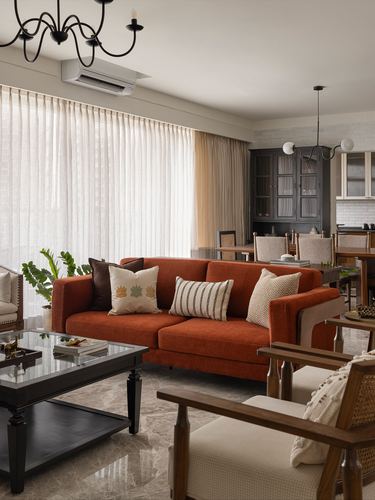 Living room with rust sofa, glass coffee table, marble floor and dining area beyond