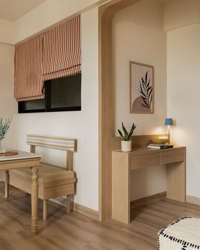 Beige foyer with wood console table under archway beside a striped-cushioned bench and window
