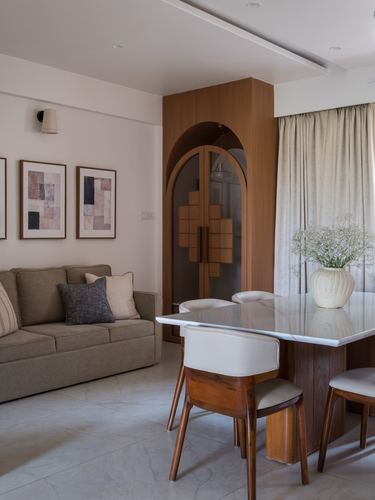Living and dining area with arched wooden wardrobe, sofa, and marble-top dining table