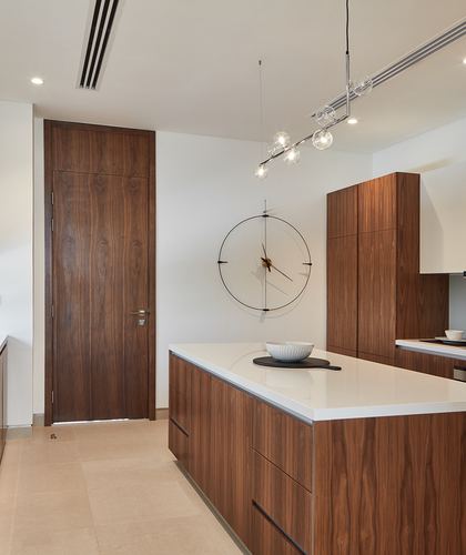 Contemporary kitchen with walnut cabinetry, white quartz island, wall clock and sputnik pendant light