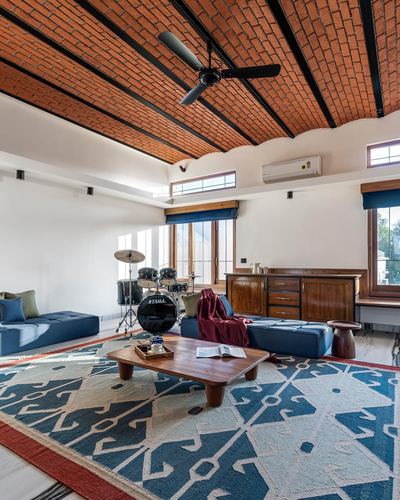 Living room with vaulted brick ceiling, blue leather sofas, drum kit and geometric kilim rug