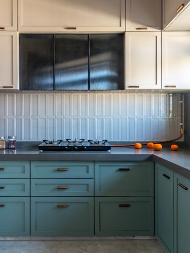 C-shaped kitchen with sage green base cabinets, grey countertop, and dark accent upper cabinet above stove