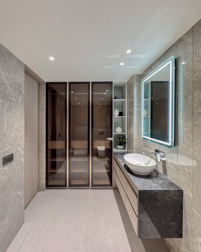 Long bathroom with stone walls, floating dark stone vanity, oval sink, and glowing backlit mirror