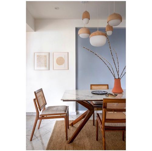 Dining nook with marble table, cane chairs, cluster pendant lights against a blue accent wall