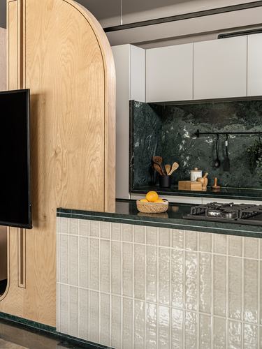 Kitchen corner with green stone backsplash, arched wood wall, and ridged tile counter front