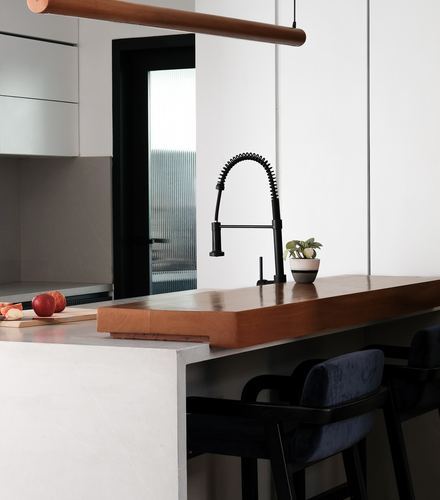 Kitchen island detail with black faucet, wood counter overlay, and navy velvet stools