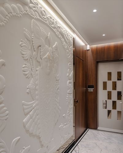 Curved white sculpted deity relief wall beside a walnut wood entry door with mirrored panel accent