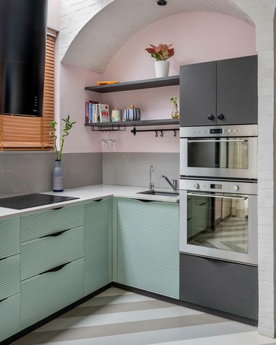 Pink and sage green kitchen corner with vaulted ceiling and built-in ovens
