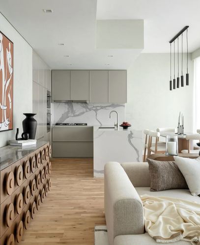 Open-plan living, kitchen and dining area with cream sofa, veined stone island and carved wood sideboard
