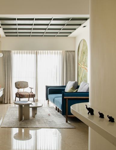 Living room with teal sofa, arched marble panel, cane chair, and gridded ceiling detail