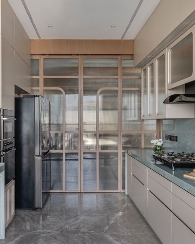 Galley kitchen with fluted glass sliding doors, black appliances, and green stone countertop