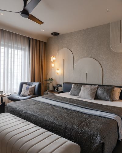 Bedroom with textured accent wall, arched fluted panels, pendant lights, and dark quilted bedding.