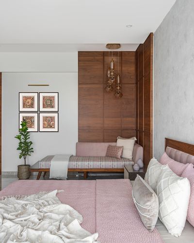 Bedroom with pink bed, wood-panelled alcove, daybed, and brass cluster pendant lights