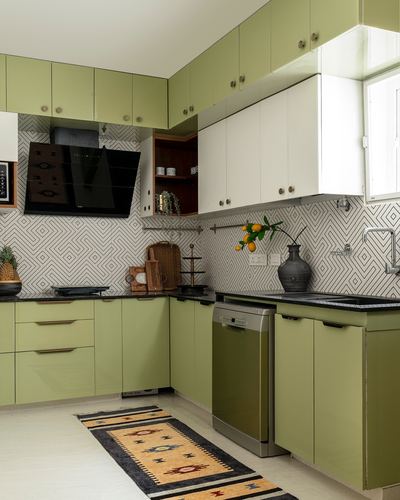 L-shaped olive-green kitchen with patterned backsplash, black countertop, and dhurrie runner on floor