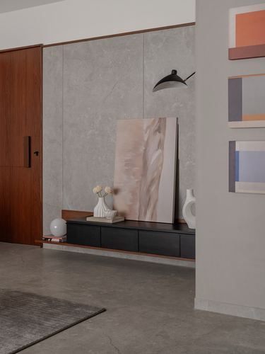 Foyer with dark floating console, leaning abstract canvas, and stone wall panel beside a wooden door