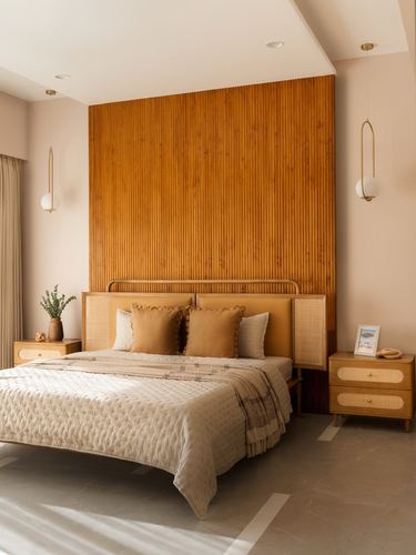 Bedroom with fluted wood accent wall, cane headboard, and matching wood nightstands lit by pendant lights