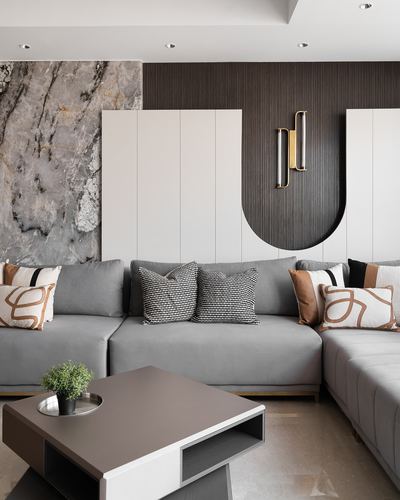 Grey sectional sofa before a marble and dark ribbed-wood feature wall with arched cabinetry cutout