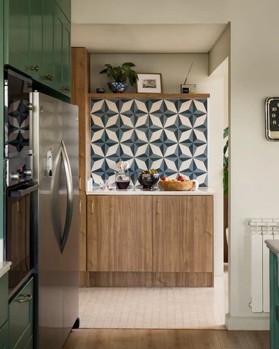 Kitchen nook with green cabinetry, wood cabinets, and blue geometric tile backsplash in a niche.