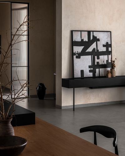 Minimalist foyer with textured plaster wall, black console, framed abstract art, and dried branches in vase