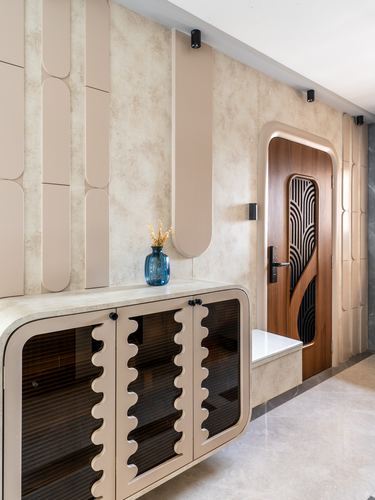 Beige foyer with wavy-edged storage cabinet and arched carved wood door