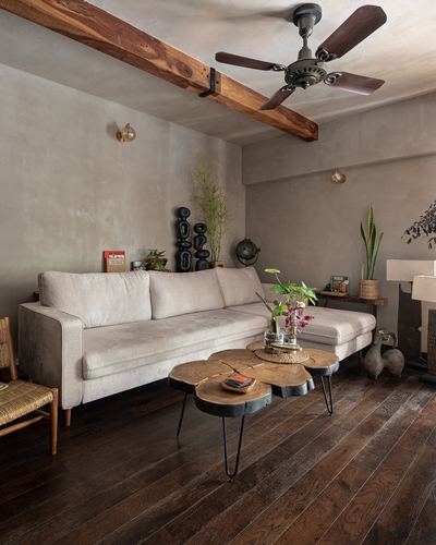 Living room with beige sofa, wood-slice coffee tables, ceiling fan on exposed beam, dark wood floor