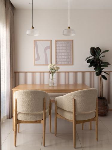 Dining table with boucle chairs beneath pendant lights against fluted wood-panelled wall