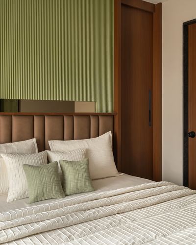 Bedroom with fluted sage green panel wall, tan channel-tufted headboard, and layered ivory bedding