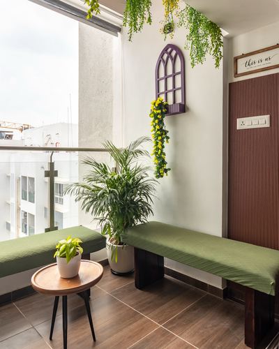 Balcony with two olive green cushioned wooden benches, potted plants, and city view