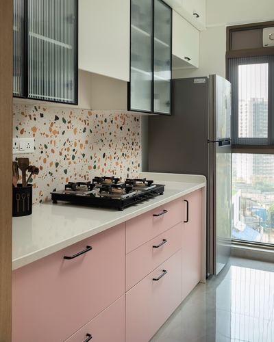 Pink kitchen cabinetry with terrazzo backsplash, white countertop, and city-view window