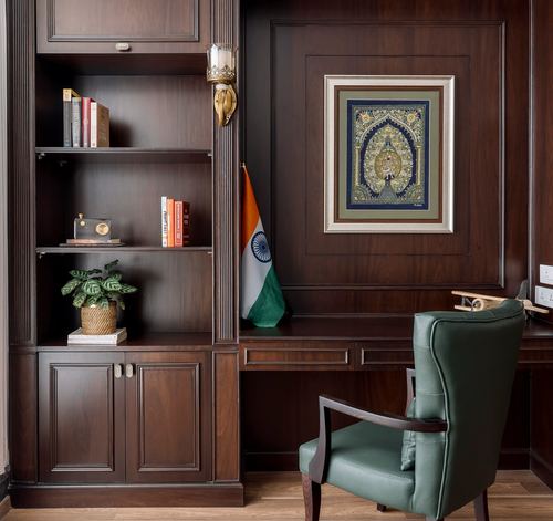 Wood-paneled study nook with bookshelf, framed miniature painting, and green leather chair