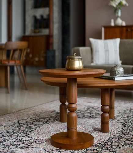 Round turned teak side table with brass pot in front of coffee table and sofa on patterned rug