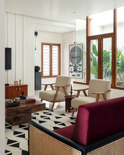Living room with cane sofa, maroon upholstery, wooden shuttered windows and courtyard view beyond