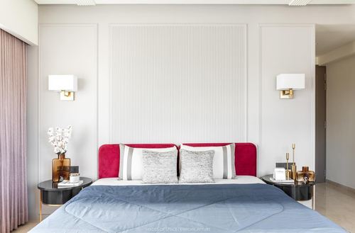 Bedroom with fluted white panel wall, magenta velvet headboard, blue bedding and brass sconces