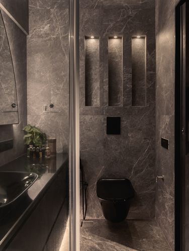 Dark grey stone bathroom with black toilet and three backlit vertical wall niches