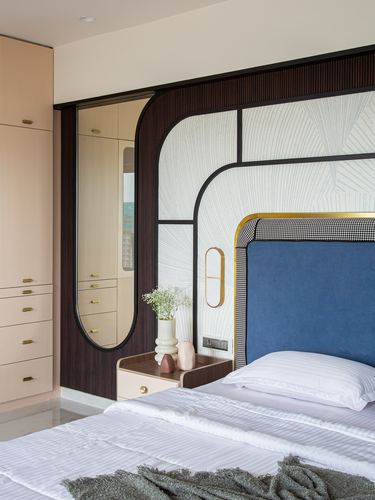 Bedroom with blue velvet headboard, arched mirror, and textured wallpaper in fluted dark wood frame