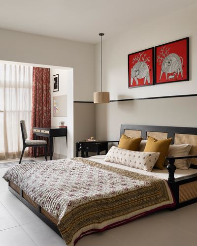 Bedroom with cane bed, kantha quilt, red elephant artwork, and study nook beyond